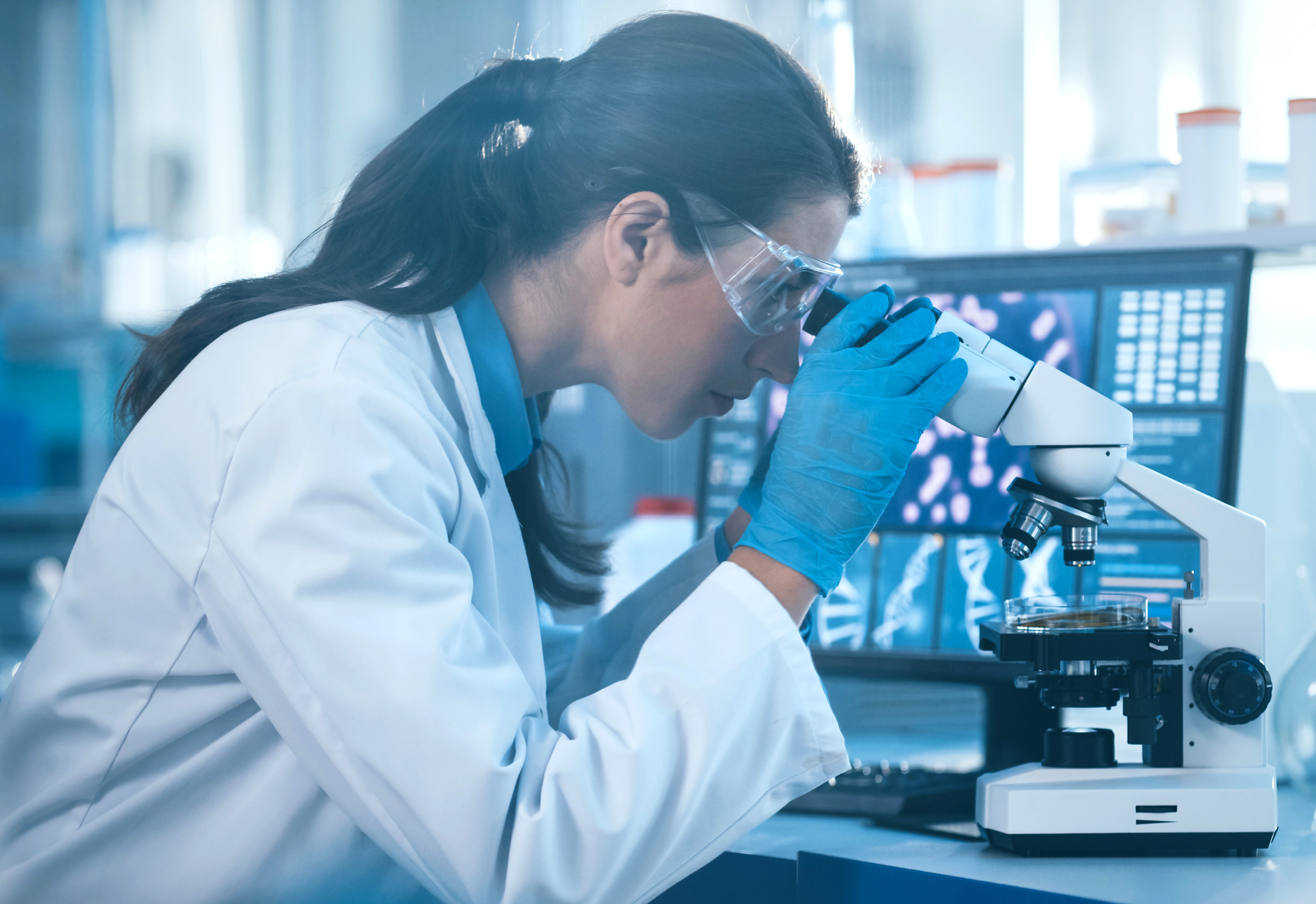 A dark-haired woman looking into a microscope