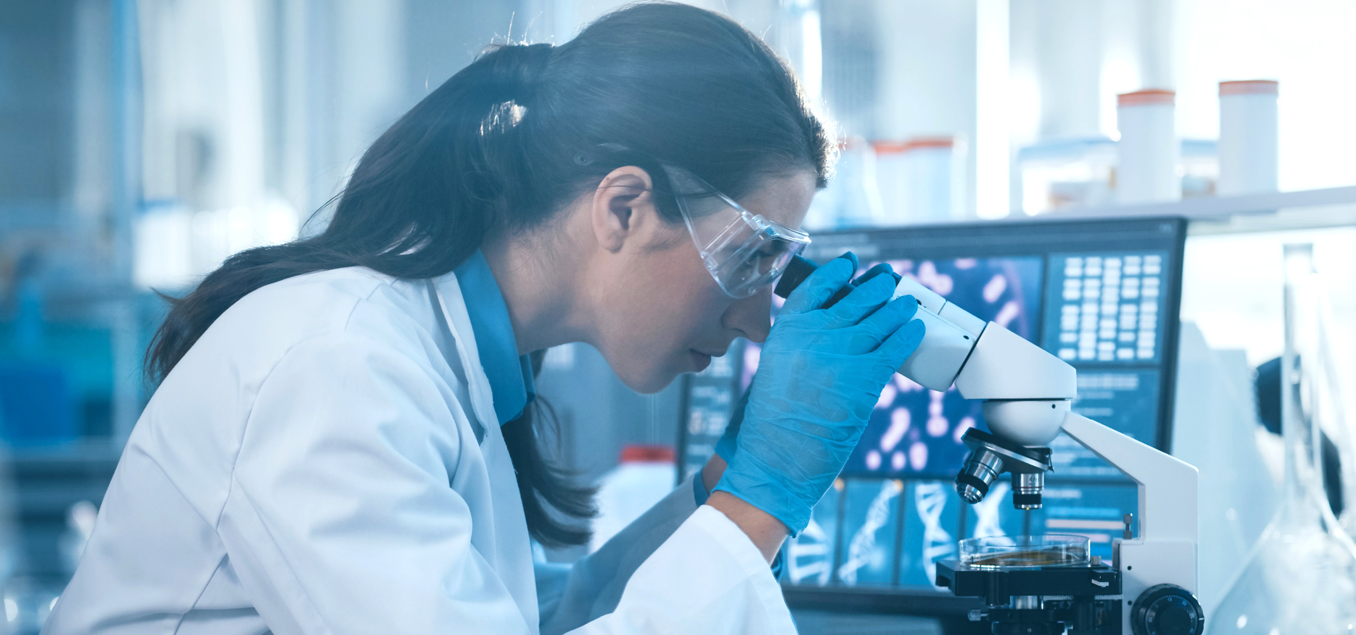 A dark-haired woman looking into a microscope