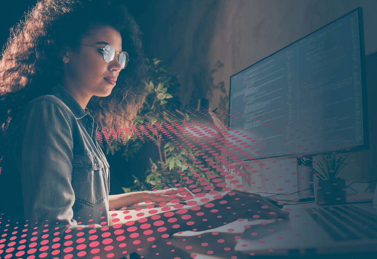 Woman coding on computer surrounded by colourful dot graphic/texture 