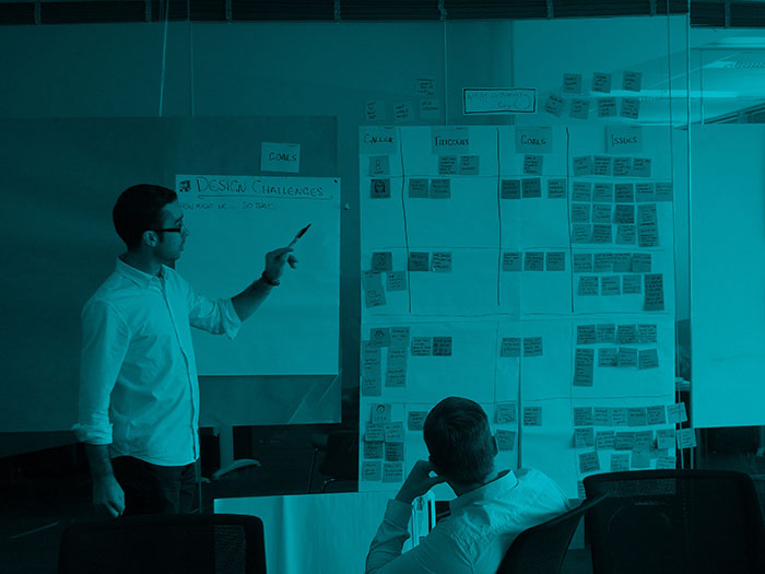 Define the problem before the solution man pointing at wall with projects cards on it