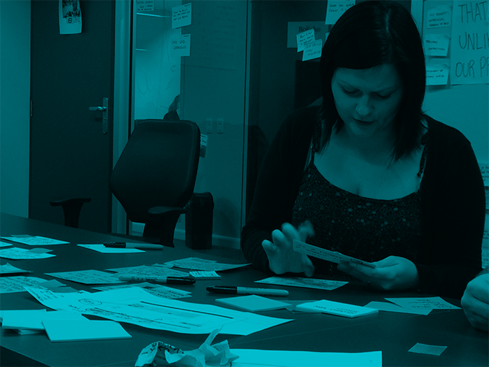 Figure out your organisational story female sitting in front of many story cards, sorting them
